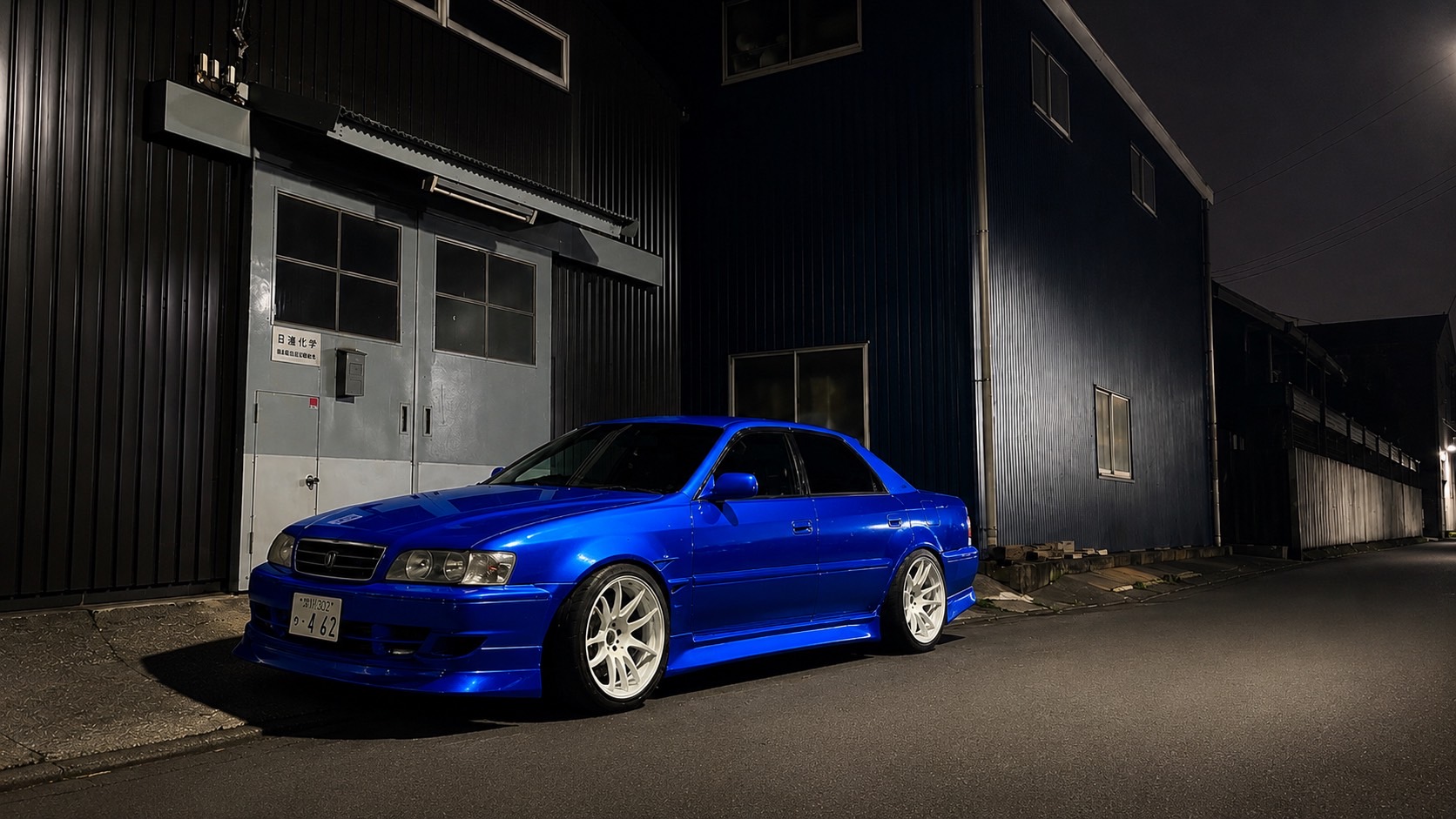 Blue modified Japanese sedan photographed at night