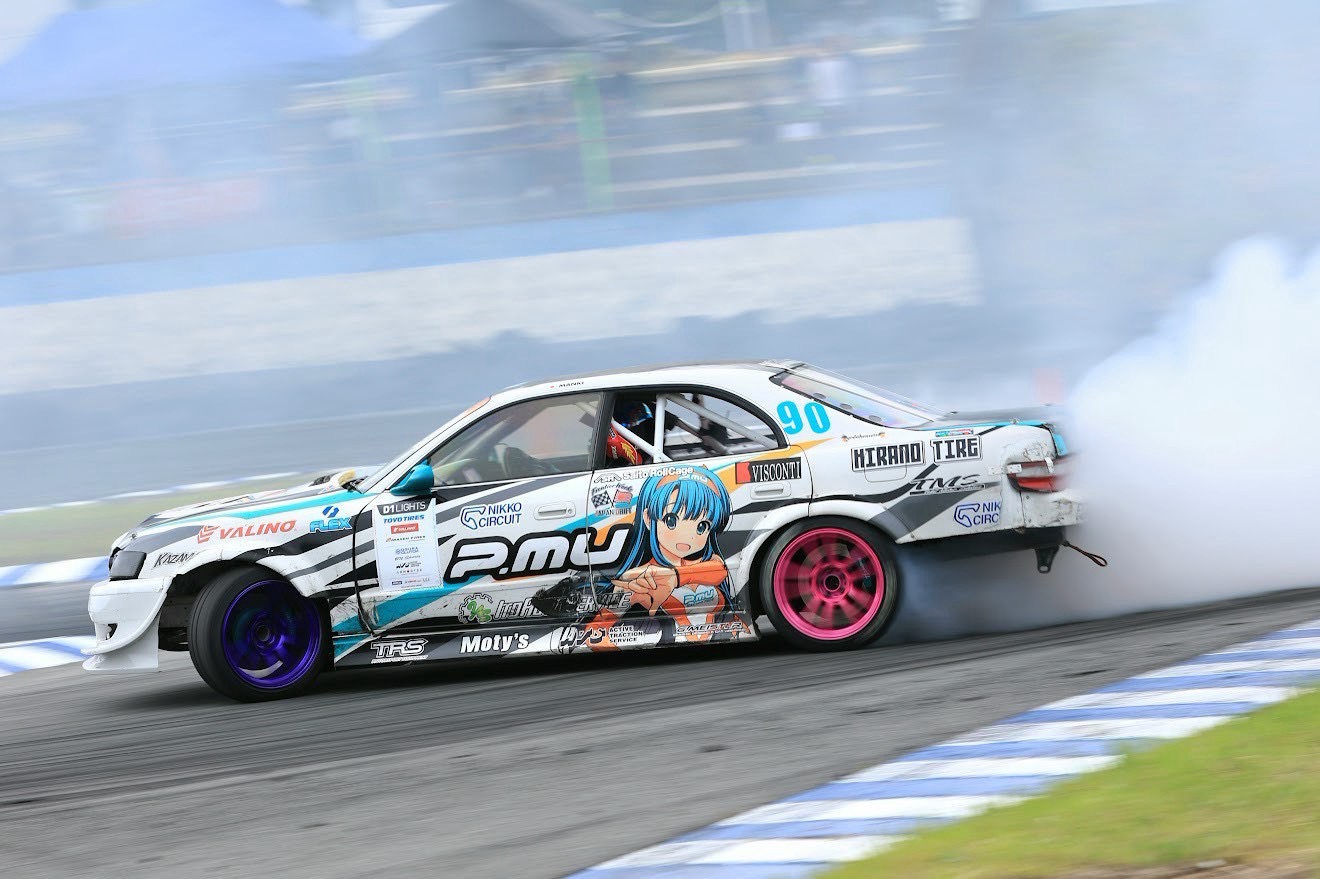 Purpose-built drift car sliding through a circuit corner with tyre smoke