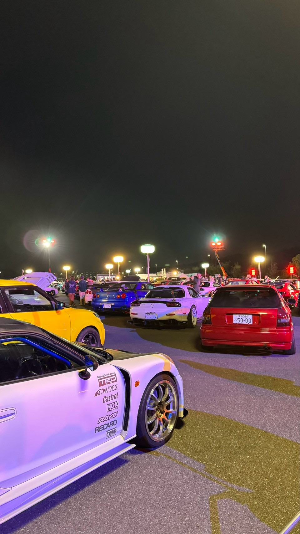 Modified cars and colourful lighting at a nighttime car gathering
